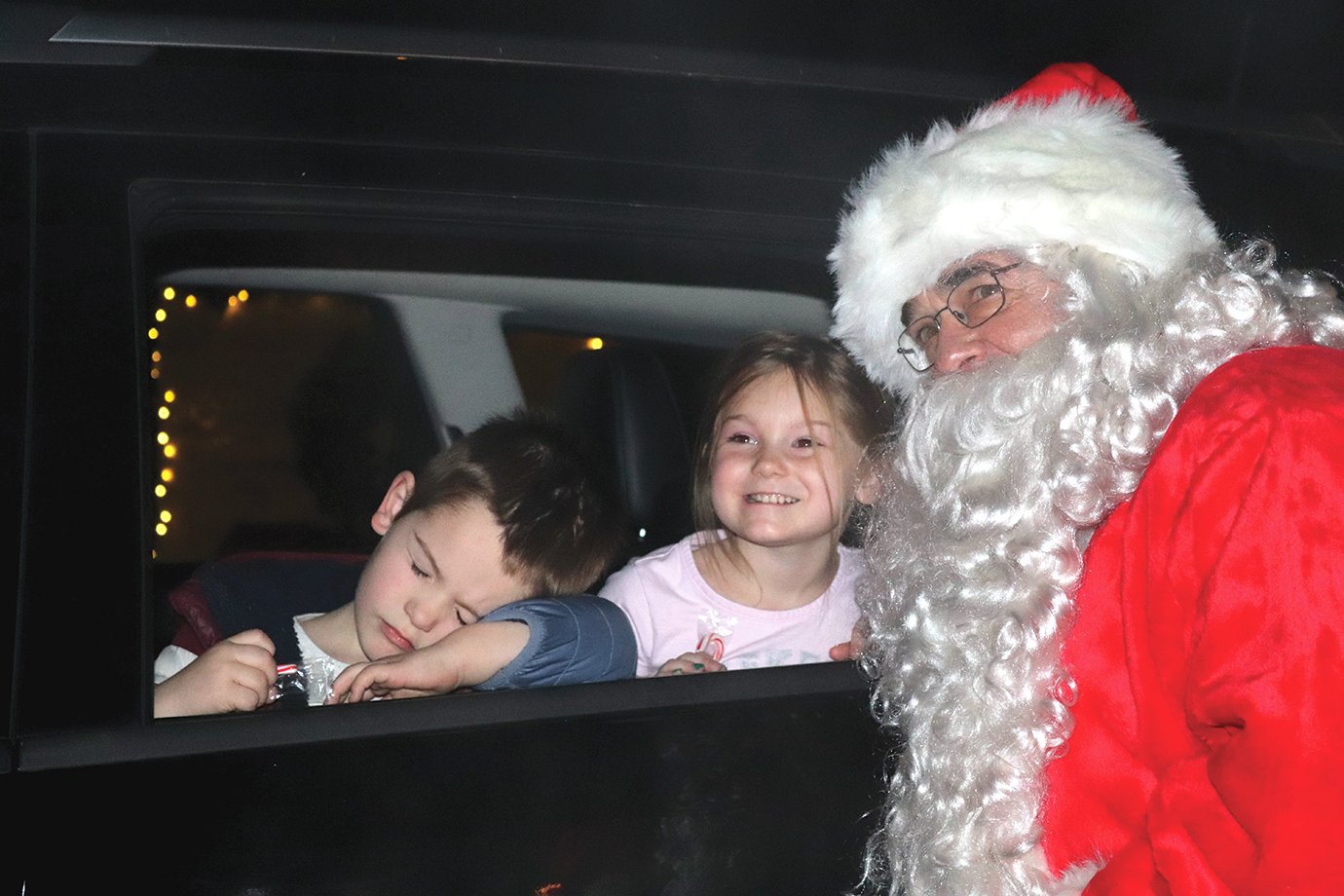 Santa and Lennon Priebe visit at the end of Christmas in the Park's drive-through event while brother Sawyer Pierce pretends to be asleep.